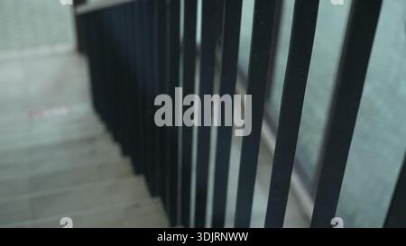 A modern interior staircase featuring a railing or banister made of vertical metal slats Stock Photo