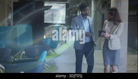 Walking professionals in business attire, discussing project in atrium with smartphone and tablet Stock Photo