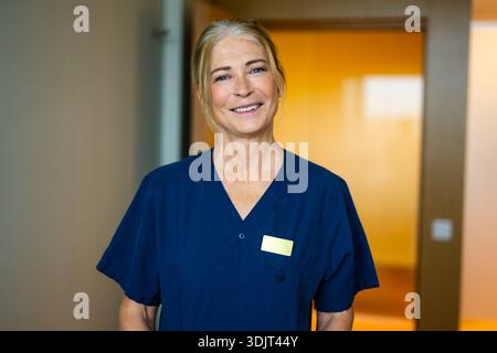 Portrait of smiling senior female doctor wearing scrubs Stock Photo