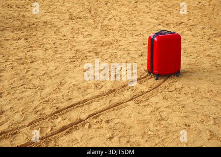 A red suitcase on a sandy beach.  Ein Bokek. Israel. Stock Photo