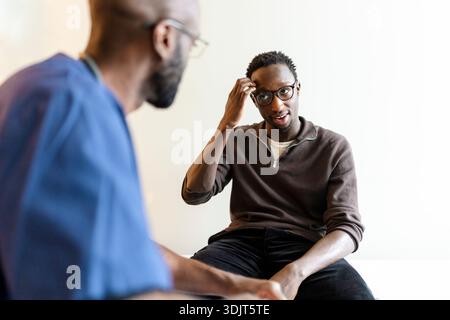 Young man with hearing disability communicating through sign language during doctor's visit Stock Photo