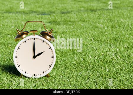 A vintage alarm clock on green grass background.Daylight saving time in spring. 3d rendering Stock Photo