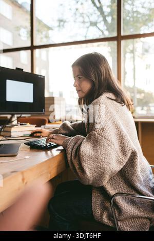 Focused mature female creative business expert working on technologies in office Stock Photo