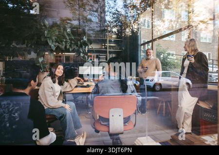 Female business expert discussing in meeting with team at office seen from glass Stock Photo