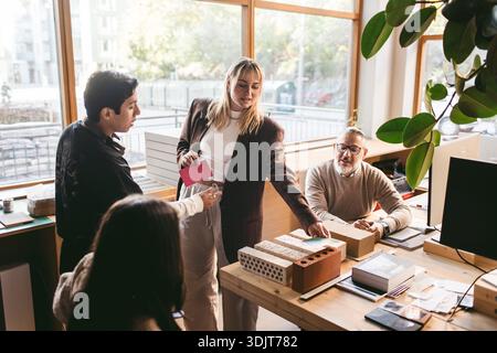 Female creative professional sharing design process with team in office Stock Photo