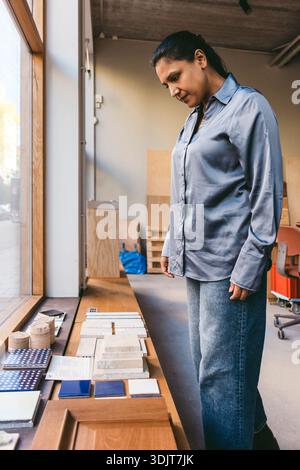 Mature female architect examining artifacts while standing in new office Stock Photo