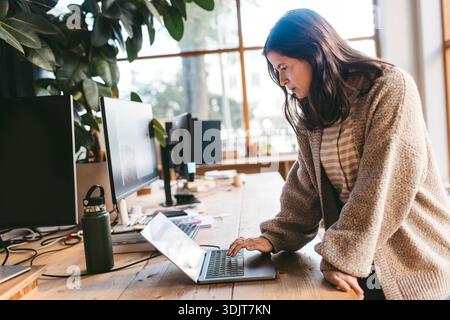 Concentrated mature female business expert working on laptop in new office Stock Photo