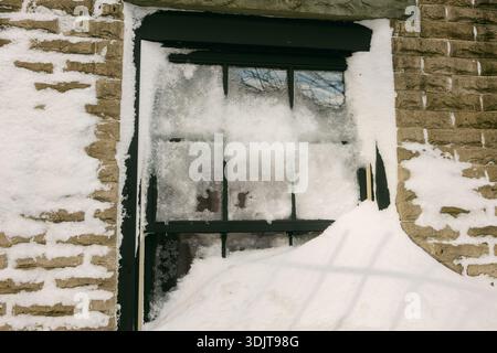 Snow blankets a window while thick layers cover the ground, showing the effects of winter weather. Stock Photo