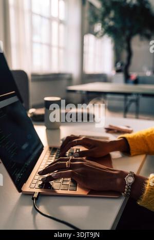 Hands of young businesswoman typing on laptop while working in tech office Stock Photo