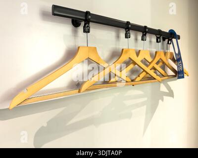 A row of wooden clothes hangers neatly arranged on a black rai inside a travelodge budget hotel uk Stock Photo