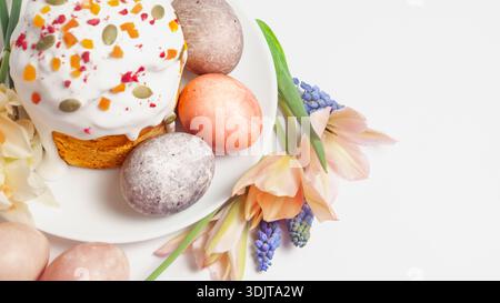 Easter cake and painted eggs decorated with flowers and seeds on a white plate Stock Photo