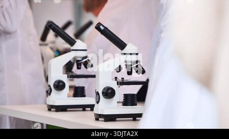 Students in lab coats using microscopes for science education Stock Photo