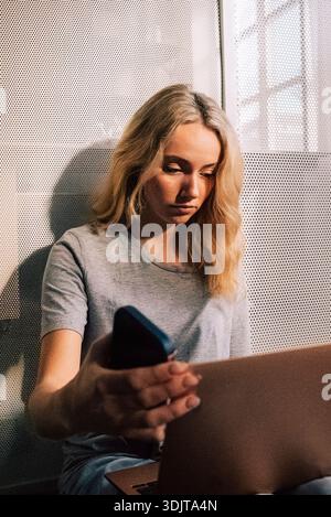 Young blond female business professional using laptop while sitting in office Stock Photo