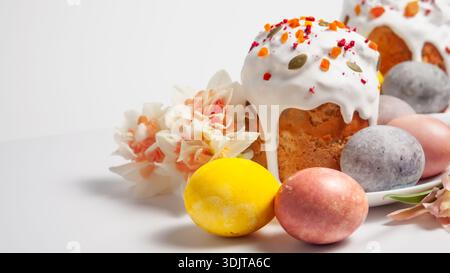 Traditional Easter cakes and painted eggs decorated with flowers and dried fruits on a white background Stock Photo