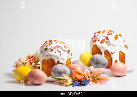 Traditional Easter cakes and painted eggs arranged with spring flowers on a white background Stock Photo