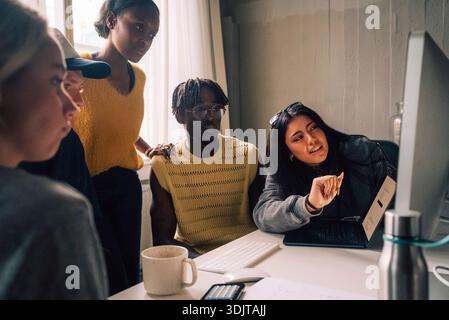 Male and female creative professional looking at computer while working in tech startup office Stock Photo