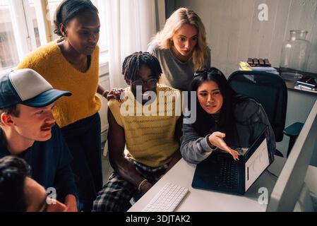 High angle view of female creative expert sharing ideas on computer with colleagues in office Stock Photo