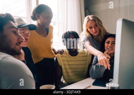 Multiracial male and female tech professionals working on desktop PC in startup office Stock Photo