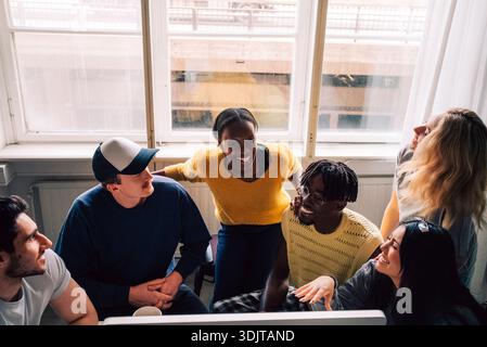 High angle view of smiling male and female tech experts talking with each other near desk in startup office Stock Photo