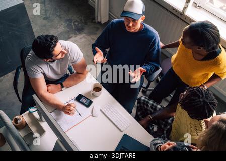 High angle view of male tech professional discussing ideas with colleagues in tech office Stock Photo
