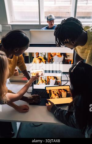 High angle view of creative professionals comparing software design preview on different technologies while working in t Stock Photo