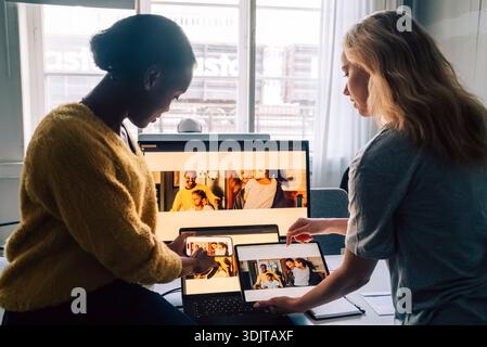 Female tech professionals checking software design preview by comparing them on different devices in office Stock Photo