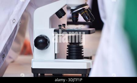 Scientists performing close-up work with microscopes in a modern science laboratory setting Stock Photo