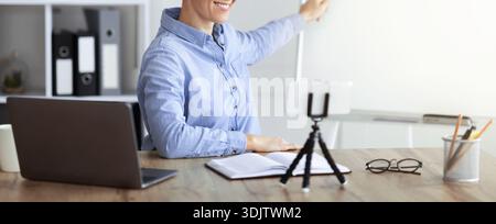 Person Presenting a Virtual Lesson While Using a Laptop and Tablet in a Modern Workspace Stock Photo