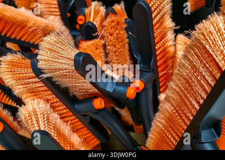 Close-up of orange bristle cleaning brushes displayed together in hardware or household supply store Stock Photo