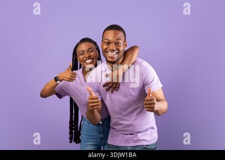 Happy black couple gesturing thumbs up and smiling Stock Photo