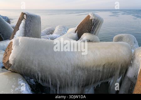 Ice-covered concrete breakwater on the Baltic Sea coast in Liepaja during a calm winter sunrise Stock Photo