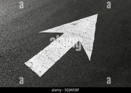 White directional arrow painted on asphalt road surface indicating forward direction. Traffic guidance symbol on street pavement. Urban transportation Stock Photo