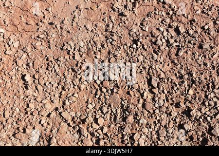 Rough rocky ground surface with small stones and gravel in natural earthy tones. Dry soil texture background with pebbles. Abstract natural terrain. Stock Photo