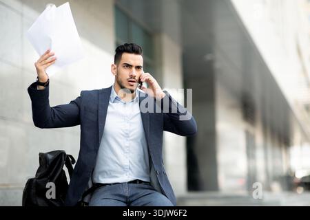 Angry middle-eastern businessman having phone conversation on the street Stock Photo