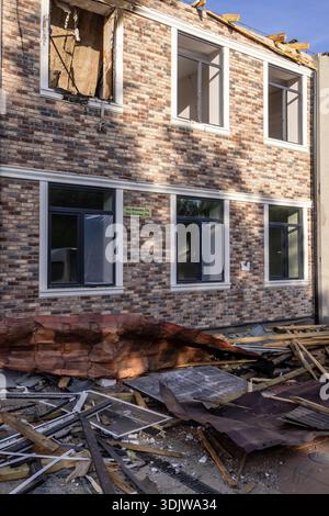 Damaged brick building with shattered windows, collapsed roof, and scattered debris; exposed interior reveals severe structural impact from destructiv Stock Photo