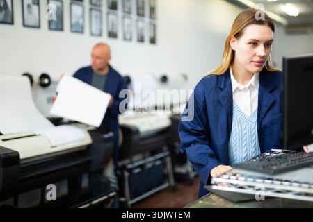 Technician operator calibrating plotter machine, typing on computer keyboard Stock Photo