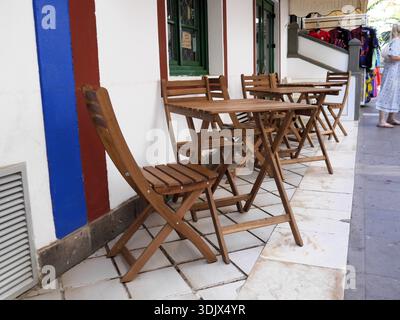 Sklum Delawar foldable acacia wood tables and chairs outside of a street café in a Mediterranean town Stock Photo
