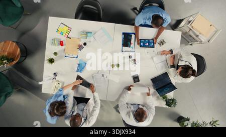 Top down view of diverse professionals collaborating in brainstorming session. Team shares medical expertise and diagnostic solutions for improved therapy at clinic. Stock Photo