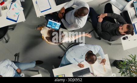 Top down view of business colleagues using computers to analyze insights and performance metrics, making projections and data visualization. Reports for corporate development. Stock Photo