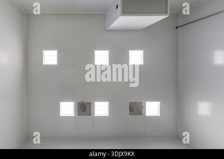 view straight up at cassette suspended ceiling with square fluorescent lights or halogen spots lamps  in a work area or hallway with ventilation Stock Photo