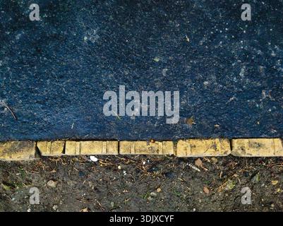 High resolution overhead view of worn asphalt meeting a dirt-filled edge at Ors vezer tere, Budapest. Gritty urban texture showcasing road wear Stock Photo