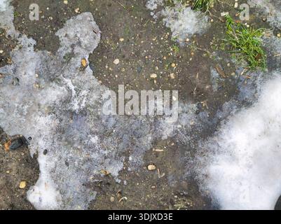 Top down view of melting snow and ice on a muddy urban surface at Ors vezer tere Budapest. Gritty seasonal texture showing the transition from winter Stock Photo