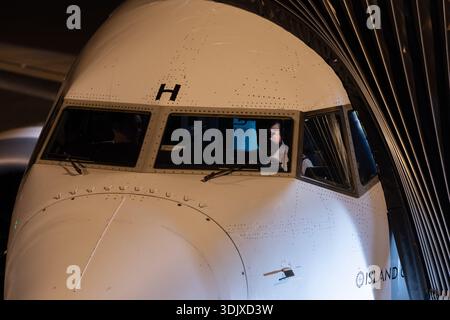 Cockpit view of a commercial jet at the gate, with pilots visible through the windshield during pre-flight preparations at night. Stock Photo