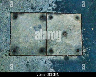 Overhead view of dual metal service hatches on Tihamer utca in Zuglo Budapest. Industrial metallic texture with weathered surfaces and mounting bolts Stock Photo