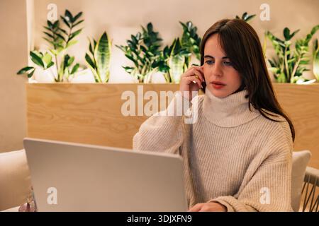 Young woman working remotely with laptop in a green modern office Stock Photo