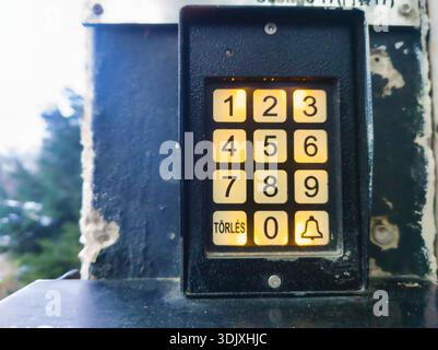 Macro view of a glowing numeric keypad at the entrance of a residential panel building in Zugló, Budapest. Features the Hungarian "TÖRLÉS" button and Stock Photo