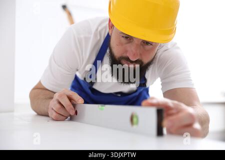 Worker measuring white dresser with building level indoors Stock Photo