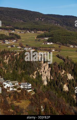 Farmland a hotel and houses near the Earth Pyramids of Ritten (Renon), a natural monument located on a plateau near Klobenstein in South Tyrol, Italy. Stock Photo
