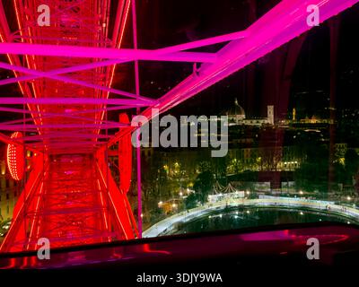 Night shot of a giant ferris wheel with  the Florence Cathedral (Duomo), with Brunelleschi's Dome and Giotto's Campanile clearly visible - Florence, I Stock Photo