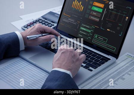Close up of a businessman's hands typing on laptop computer keyboard analysing business investment information on a desktop in an office setting Stock Photo